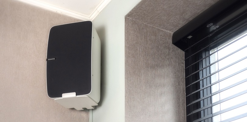 Une enceinte blanche est fixée au mur près de la fenêtre à l'aide d'un support d'enceinte.