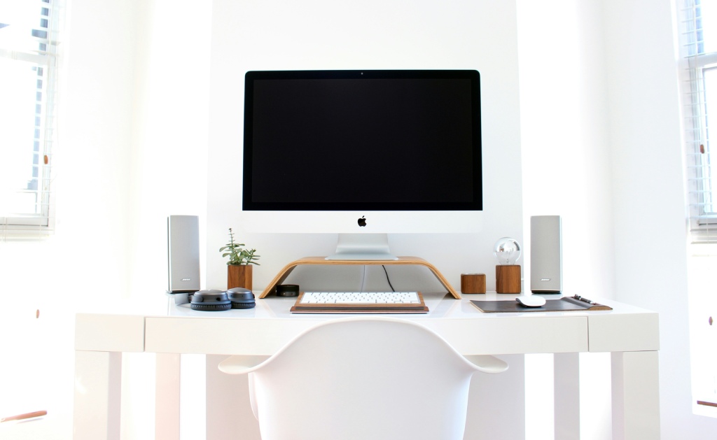 Un intérieur blanc moderne avec un bureau équipé d'un ordinateur et de deux haut-parleurs de chaque côté.